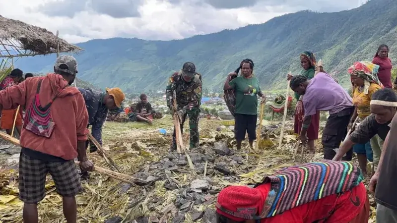 Prajurit Satgas Yonif 112/DJ membantu warga Papua menata batu untuk tradisi bakar batu di Puncak Jaya. (Foto;Dok/Kodam.IM)