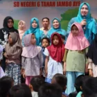 Marlina Muzakir (Kak Na) membagikan seragam sekolah kepada siswa korban banjir Aceh Utara. (Foto:Dok/Ist)