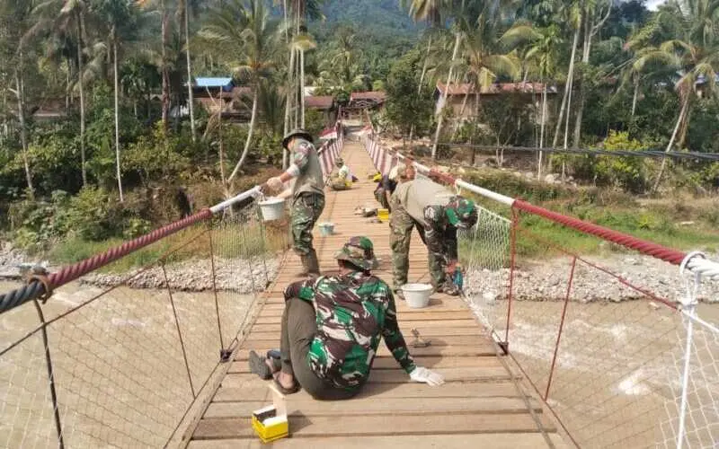 Babinsa dan warga mengecat Jembatan Gantung Perintis di Ketambe. (Foto:Dok/Kodim 0108)